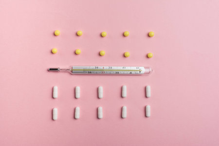 Illness concept: thermometer and tablets on a pink background top viewの写真素材