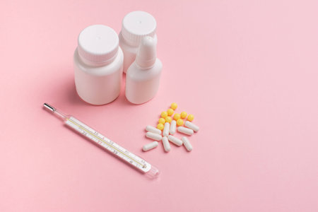 Concept Illness: thermometer,  vitamins and tablets in a jar on pink backgroundの写真素材
