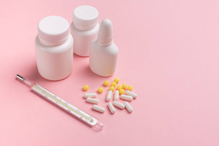 Creative concept Illness: thermometer,  vitamins and tablets in a jar on pink backgroundの写真素材