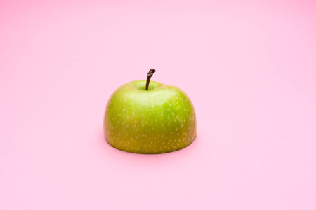 Half a green apple on pastel pink background. The concept of diet and weight loss.の写真素材