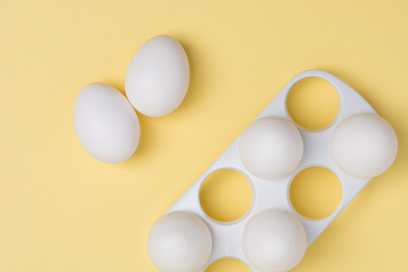 Happy Easter concept. White eggs on yellow background close up. Flat lay. Minimal concept. Top view....