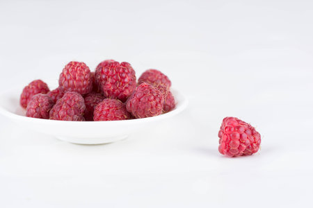 Fresh ripe raspberries on a plate on a white background. Close-up, minimal concept of fashion foodの写真素材