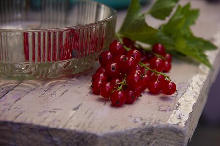 Bowl of freshly picked red currants and leaves on a pink benchの写真素材