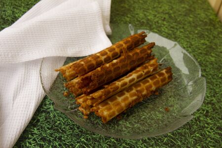 homemade wafer rolls lie on a transparent plate on the grass. next to a snow-white napkin. dessert on nature. sweets time.の写真素材