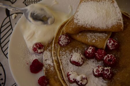 pancakes on a plate with raspberries and sprinkled with powdered sugar. Holiday - Shrovetide.round treat.の写真素材
