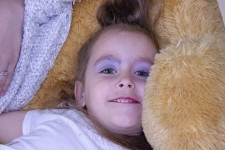 girl with a teddy bear on the bed in the roomの写真素材