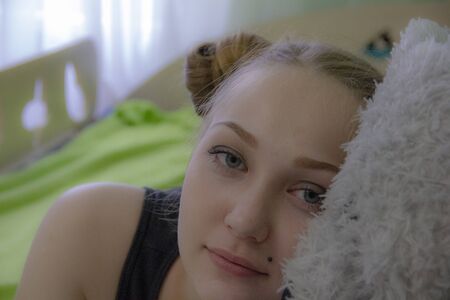 girl with a teddy bear on the bed in the roomの写真素材