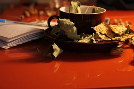 Great, beautiful autumn background. dry autumn oak leaves in a brown mug and on a plate. Nearby lies a notebook. Copy space.の写真素材