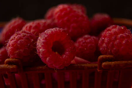 Raspberry berries lie in a plastic brown basket. filmed in a dark way.の写真素材