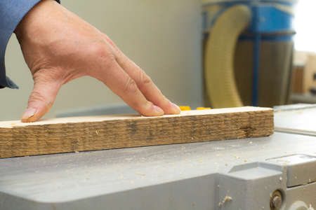 an elderly carpenter handles the bar on the machine. mens work with tools.