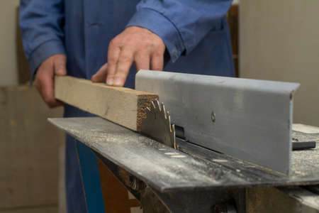 an elderly carpenter handles the bar on the machine. mens work with tools.