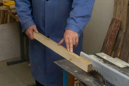 an elderly carpenter handles the bar on the machine. mens work with tools.