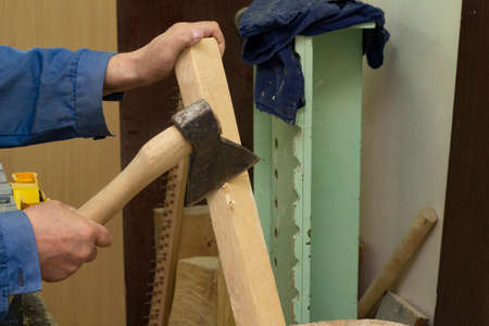 A gray-haired man in work clothes works with an axe. chops the log. carpenters job