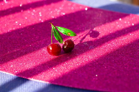 Two cherries joined lie on a pink backgroundの写真素材