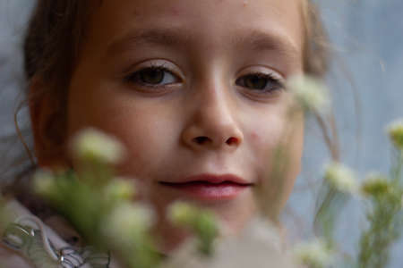 portrait of a cute little girl through the flowers that stick out of the bookの写真素材