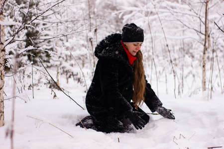 Beautiful sexy girl tosing snow. around the trees in the snowの写真素材