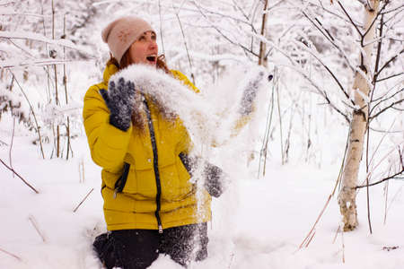 Beautiful sexy girl tosing snow. around the trees in the snowの写真素材