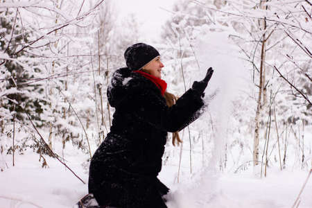 Beautiful sexy girl tosing snow. around the trees in the snow