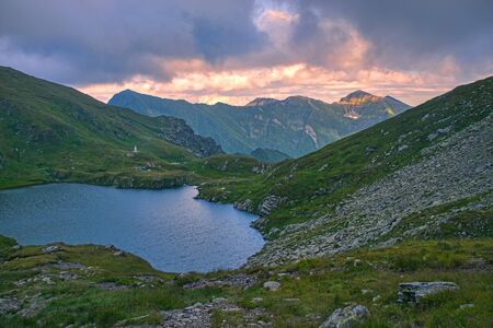 Summer mountain lake, Capra lake in Romanian Carpathians, sunset skyの写真素材