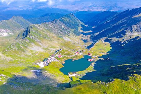 Balea landmark viewed from above: lake, chalets and Transfagarasan road in a summer landscape