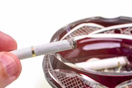 Man hand holding cigarette over ashtrayの写真素材