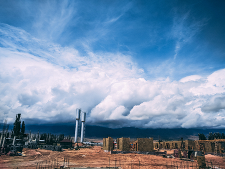 Construction process on the background of mountains. two water towers. Cloudyの写真素材