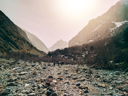 Mixed group of athletes men and women are young and walk along a stone path among the mountains. Sun rays. rocks on both sidesの写真素材