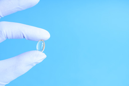 Hand in a white glove holds a transparent tablet on a blue pastel background