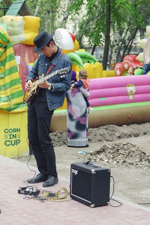 BISHKEK, KYRGYZ REPUBLIC - APRIL 14, 2018: Handsome man with guitar on street in front of air...