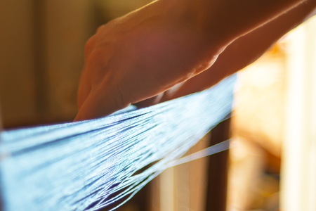 Woman spooling yarn in the manufacture studio at home. Handmade.の写真素材