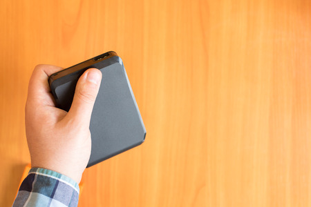Man holds an external hard drive above the tableの写真素材