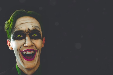 Cosplay of a cult character from comics. Joker laughs in the dark. Halloween holidays. Copy space...