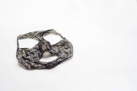 The removed layer of the black mask lies on a white surface. Sunny day, Top view with copy space for textの写真素材