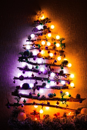 Christmas tree made from twigs and sticks with purple and orange lights at night.の写真素材