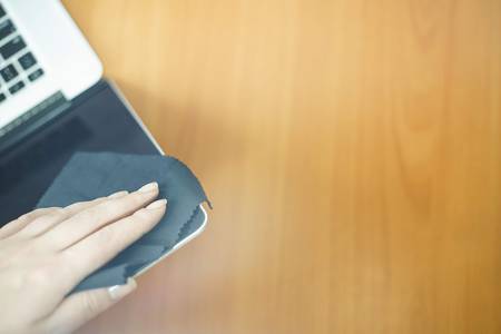 Close up of woman hands cleaning laptop screen with black rag. top view with copy space for text