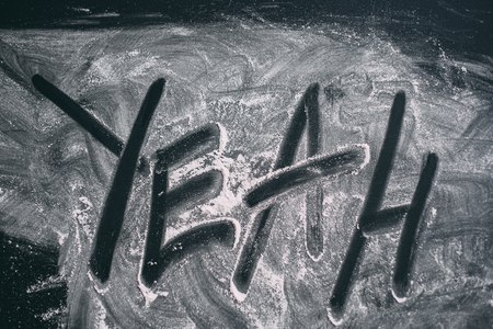 Ripped powder in the form of the word "yeah" on a black table top viewの写真素材