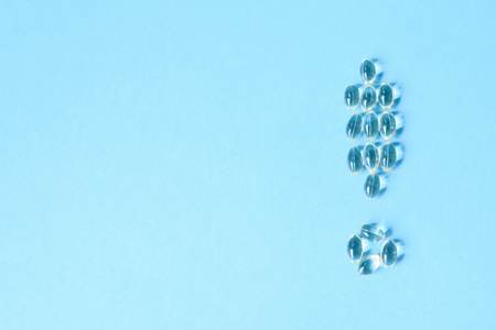 Sapphirine pills laid out in the form of an exclamation mark on a blue background. Flat lay