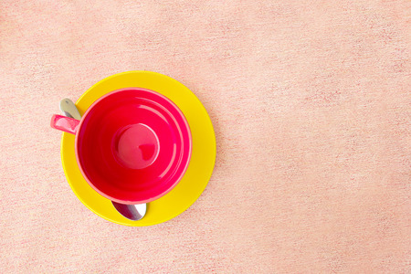 Red cup on yellow plate on pink tablecloth. Top viewの写真素材