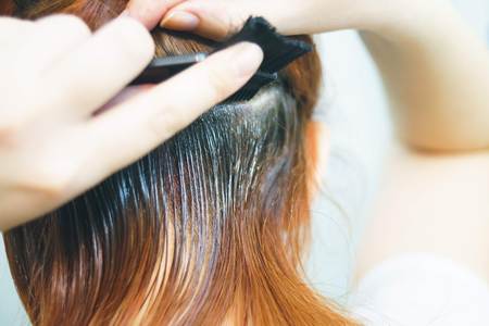 Close up woman dyed the girls red hair on white backgroundの写真素材