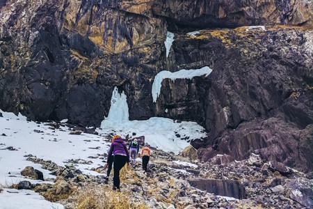 Hiking in the mountains in winter. Backpackers walking on snow-covered mountain slope. Complicated weather conditions. A group of tourists and on a winter walk in the winter path.の写真素材