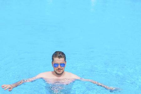 Man is walking in the water in the swimming pool. Man swim in the pool at the hotel. View from above.の写真素材