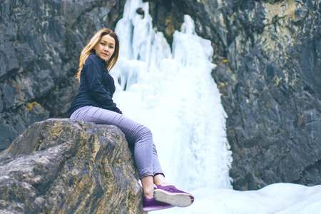 The woman sitting on the rock mountain. The female sits in the mountains on a rock and admires the beautiful views of the mountains.の写真素材
