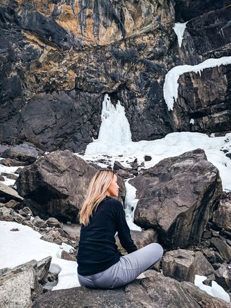 The woman sitting on the rock mountain. Young yoga woman sit meditation on sunrise mountain peak rock.の写真素材