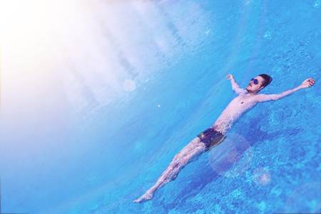 Man floating on the water in the swimming pool. Male swim in the pool at the hotel. View from above. Relax conception.の写真素材