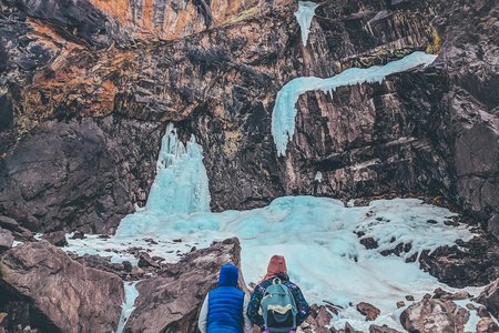 Hiking in the mountains in winter. Backpackers walking on snow-covered mountain slope. Complicated weather conditions. A group of tourists and on a winter walk in the winter path.の写真素材