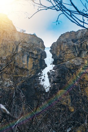 Ice waterfall in the peak slope. Frozen snow at mountain cliff at waterfall in winter season.の写真素材