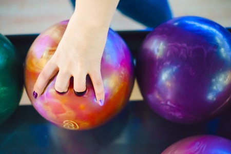 The human hand holds an orange bowling ball. Vivid colors. Summer day,の写真素材