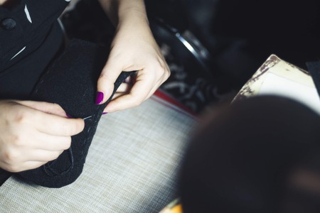 Close up women's hands of seamstress at work with material fabric