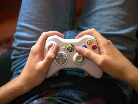 Bishkek, Kyrgyzstan - July 16, 2017: Guy plays the console. Gaming game play tv fun gamer gamepad guy controller video console playing player holding hobby playful enjoyment.のeditorial素材