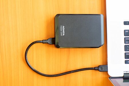 Portable external hard drive on the desk near the laptop. External Hard with Laptop on wooden backgroundのeditorial素材